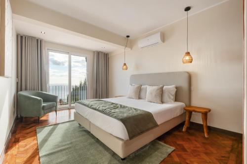 a bedroom with a bed and a chair and a window at Funchal Bay View Villa by Homie in Funchal