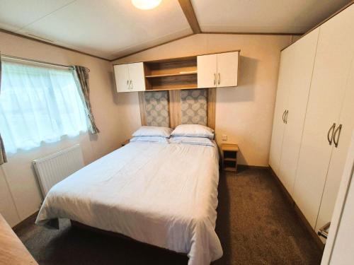 a bedroom with a bed with white sheets and a window at Dornoch Holiday Chalet in Proncy