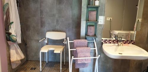 a bathroom with a sink and two chairs and a mirror at Gîte d'Anne et Ulysse in Sept-Frères