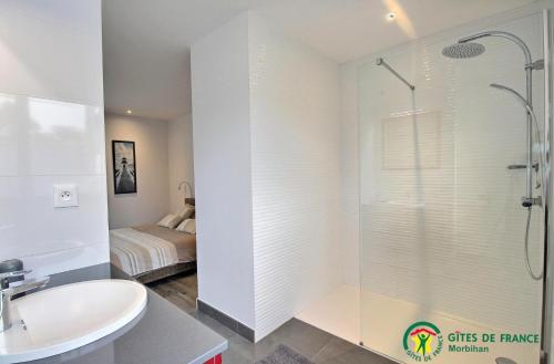 a bathroom with a shower and a sink and a bed at Ty moncher côté cour in Plouhinec