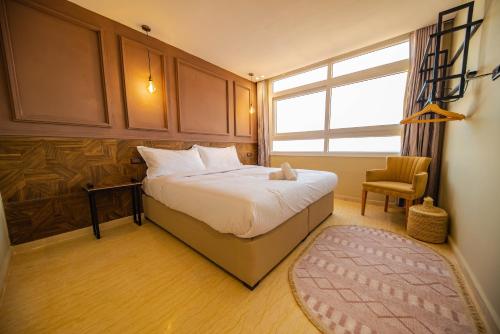 a bedroom with a bed and a chair and a window at Singular Hotel, SH Dakhla in Dakhla