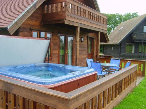 a large hot tub on a deck of a house at Melbury Chalet in West Stour