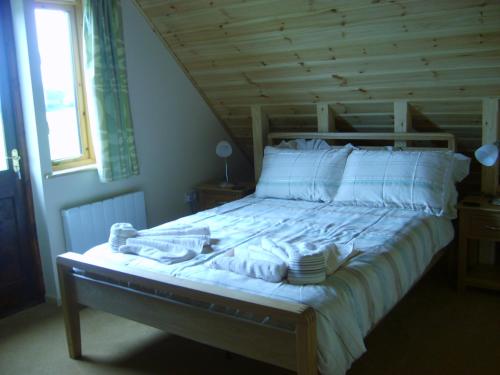 a bed with white sheets and towels on it at Melbury Chalet in West Stour