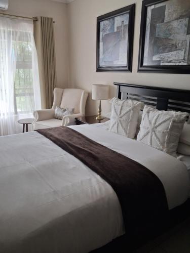 a bedroom with a large white bed and a chair at The Ridge BnB in Manzini