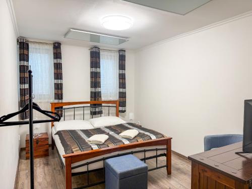 a bedroom with a bed and a desk and a television at Sommeliérka - ubytování & vinný sklep in Valtice