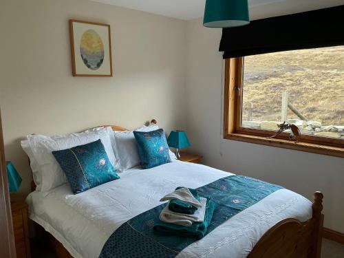 a bedroom with a bed with blue pillows and a window at Apartment 2, Craigmore, Upper Baila, Lerwick in Lerwick