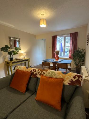a living room with a couch with orange pillows at The Garden Haven in Cheddar