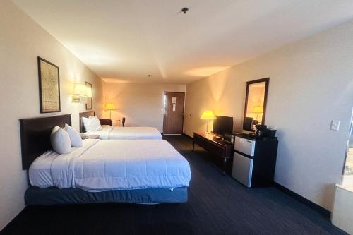 a hotel room with two beds and a television at Osage Village Inn Near Lake Ozarks US 54 in Osage Beach