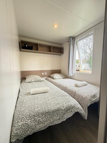two beds in a small room with a window at Chez Maxime - E33 - Clim TV Lave-vaisselle - Proche Europa Park et Rulantica in Boofzheim
