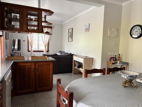 a kitchen and living room with a table and a clock at Quinta das Palmeiras in Povoação