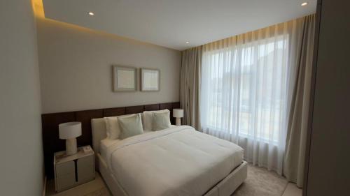a bedroom with a white bed and a large window at Hatta Residence in Hatta