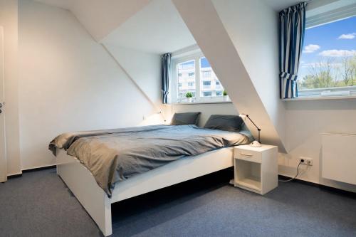 a bedroom with a white bed and two windows at fewo1846 - Baltic Lodge - komfortable Maisonettewohnung mit 3 Schlafzimmern, Balkon und Blick auf die Marina Sonwik in Flensburg