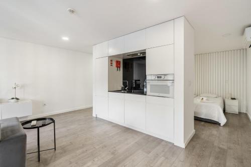 a white room with a kitchen and a couch at PALHOTAS GUEST HOUSE - Apartamento Sameiro in Braga