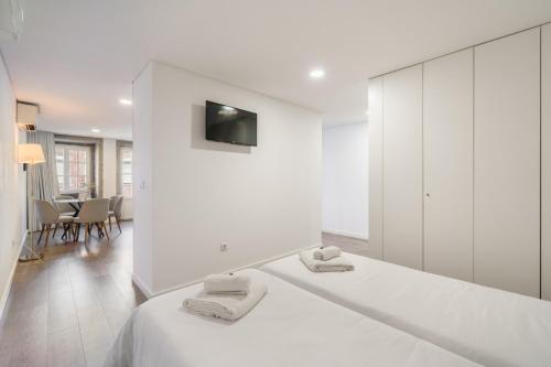 a white bedroom with a large white bed with a mirror at PALHOTAS GUEST HOUSE - Apartamento Sameiro in Braga