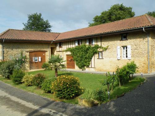 a brick house with a garden in front of it at Logis Le Relais du Bastidou in Beaumarches