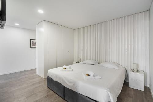 a bedroom with a large white bed with two towels on it at PALHOTAS GUEST HOUSE - Apartamento Palhotas in Braga