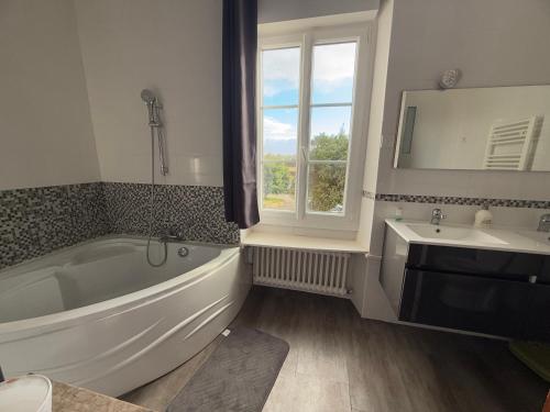 a bathroom with a large tub and a sink at Demeure Saint Gildas in La Haye-Pesnel