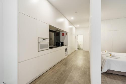 a white kitchen with white walls and wooden floors at PALHOTAS GUEST HOUSE - Apartamento Jardim Santa Bárbara in Braga