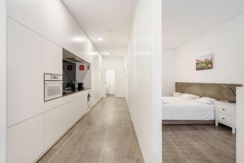 a white bedroom with a bed and a kitchen at PALHOTAS GUEST HOUSE - Apartamento Jardim Santa Bárbara in Braga