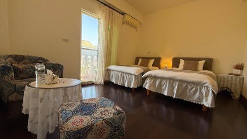 a room with two beds and a couch and a table at 金門58旅宿 可包棟 好停車 近市區 近金門大橋 in Hsia-pu-hsia