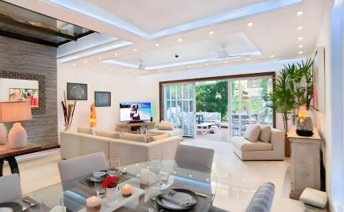 ein Wohnzimmer mit weißen Möbeln und einem Glastisch in der Unterkunft Luxury Duplex 2BR Pool & Garden View Quiet 30m from 5th Ave with Gym & Parking in Playa del Carmen