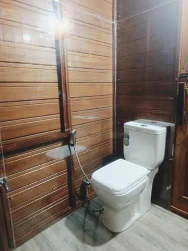 a bathroom with a toilet and a wooden wall at Velya cabana in Belihuloya