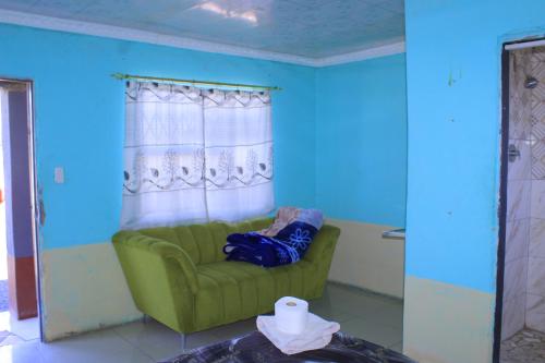 a green couch in a room with blue walls at Equatorial Guest House in Rustenburg