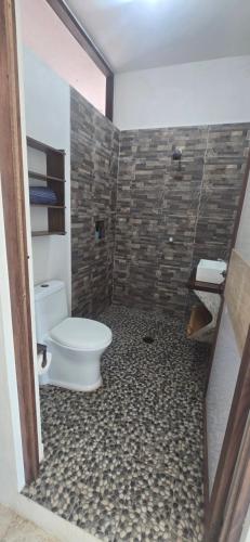 a bathroom with a toilet and a stone wall at Casa Laud Cuarto Guamuchil in Guayabas