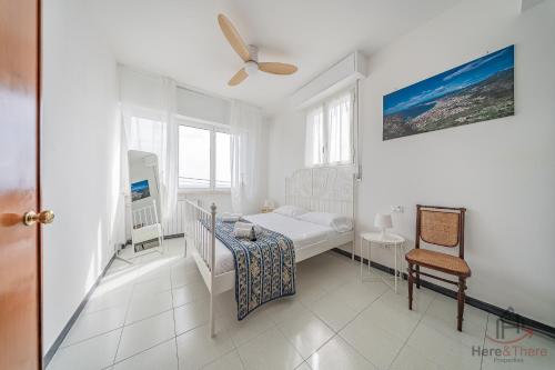 a white bedroom with a bed and a chair at Sea Dream - Vista Mare - Giardino - Box Privato in Bergeggi