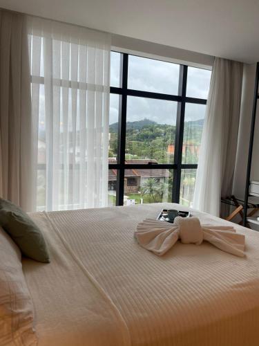 a bedroom with a large bed with a large window at Apartamento Dein Haus in Pomerode