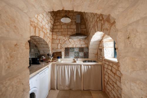 a large kitchen with a stone wall and a counter at Trullo Elisa in Monopoli