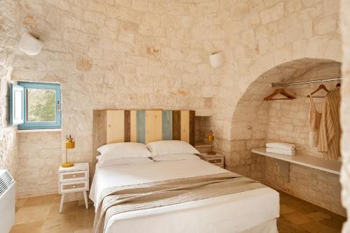 a bedroom with a large bed in a stone wall at Trullo Elisa in Monopoli