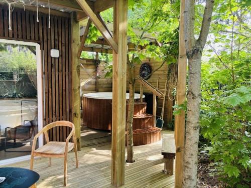 a wooden deck with a tub and a chair at NÜ-DE GITES ET SPA in Zuydcoote