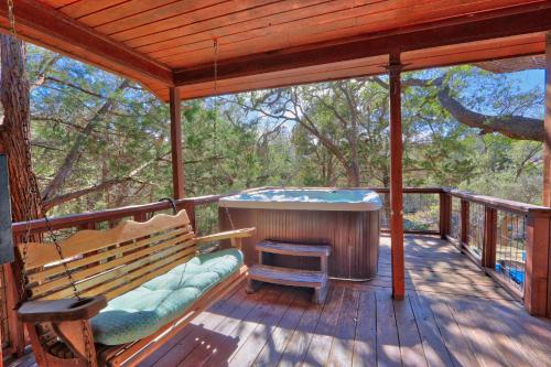 a porch with a hot tub and a bench on a deck at Falls Log Home in Wimberley