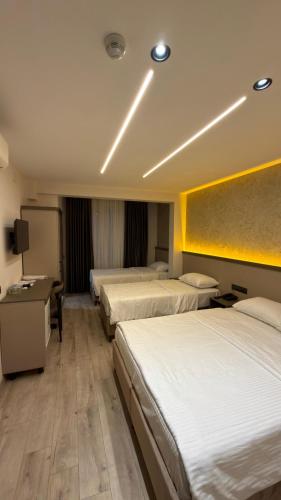 a hotel room with three beds and a television at Dostlar Hotel in Mersin