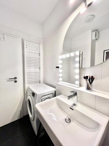 a white bathroom with a sink and a washing machine at Studio Nuppu Comfort, AC in Trnávka