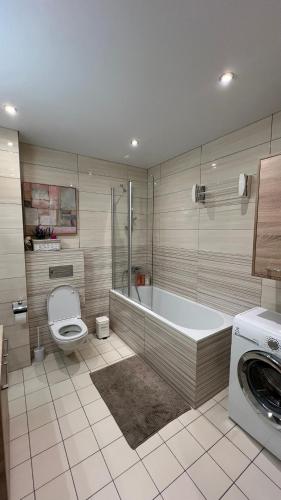 a bathroom with a tub and a toilet and a sink at DO Apartments in Druskininkai