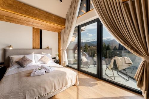 a bedroom with a bed and a large window at CHATAR Tatra Premium Suites in Zakopane