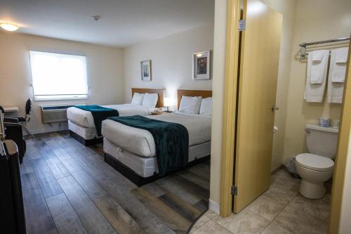 a hotel room with two beds and a toilet at Sleep Suite Motel in Steinbach