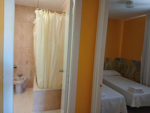 a bathroom with a shower and a bed and a toilet at Hotel Millan in Negreira