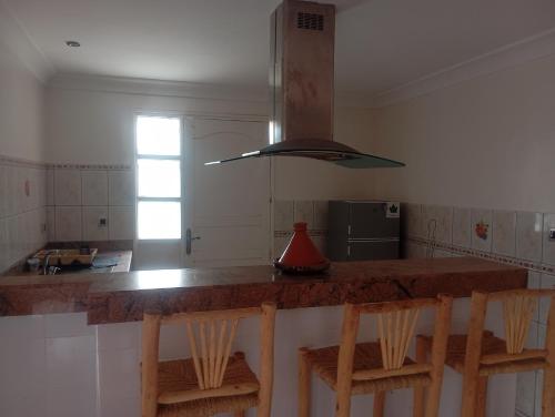 a kitchen with a counter with chairs and a stove at amazigh soul experience in Mirleft