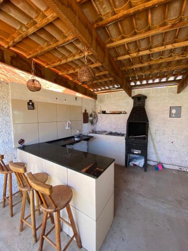 a kitchen with a counter and two chairs and a stove at Casaacochego in Icapuí