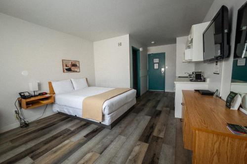 a bedroom with a bed and a desk and a tv at Sleep Suite Motel in Steinbach