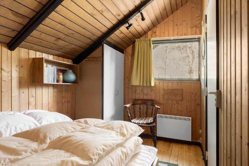a bedroom with two beds and a window and a chair at 2614-Romo-Stormengevej-18 in Høm