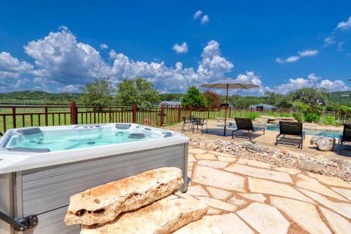 a hot tub on a patio with chairs and a pool at D2 Farms Main House in Wimberley