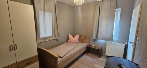 a small bedroom with a bed with a pink pillow at Pension Raunheim in Raunheim