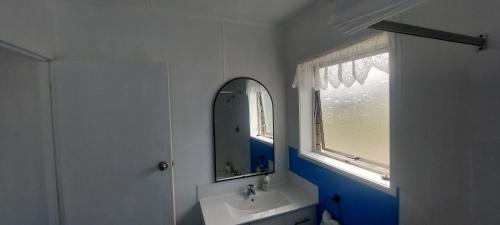 a bathroom with a sink and a mirror and a window at Fantastic Two Bedroom Unit in Whakatane