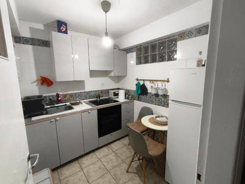 una piccola cucina con armadi bianchi e tavolo di Kipsely room ad Atene