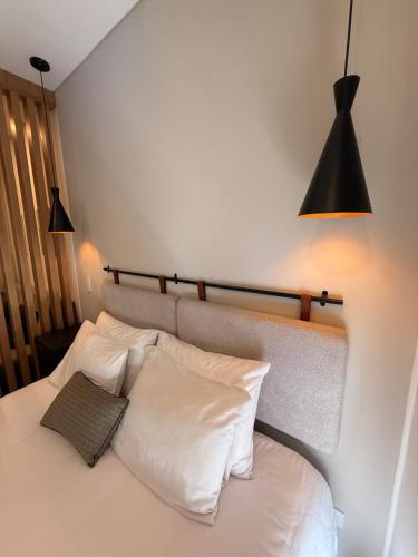 a bed with two pillows and two lights above it at Apartasuite Cowork in Bogotá