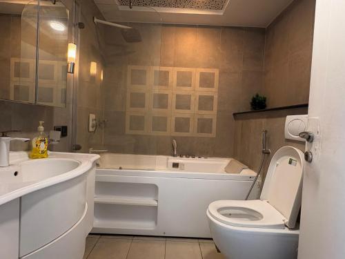 a bathroom with a tub and a toilet and a sink at MZK Apartment in Islamabad